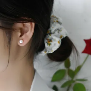 Close-up detail of a classic round freshwater pearl stud earring worn on ear