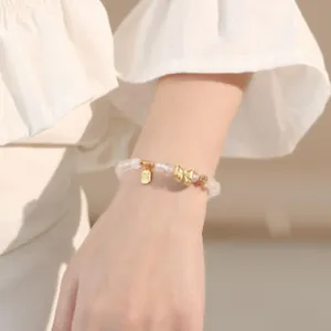 Makro-Detail des lavendelfarbenen Amethyst-Perlenarmbands mit goldenem Schleifen-Anhänger