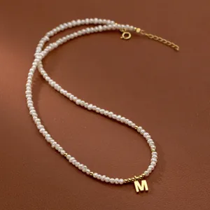Close-up detail of a vintage freshwater pearl necklace with a golden initial M pendant