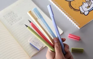 Macro shot of colorful inkless eternal pencils held over an open notebook detail view