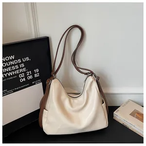 Detailed view of cream-colored hobo bag with contrast brown straps in a minimalist lifestyle setting