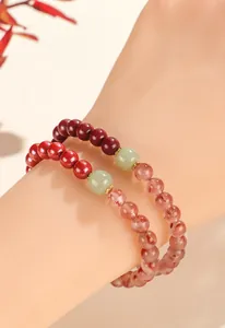 Close-up detail of beaded bracelet with cinnabar, strawberry quartz and jade on wrist