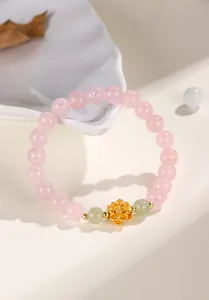 Macro detail of a lotus charm bracelet with strawberry crystal and Hetian jade beads