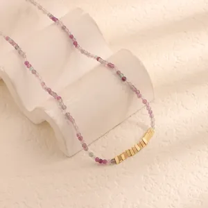 Dettaglio macro di una collana di perle naturali viola con inserti dorati lucidi