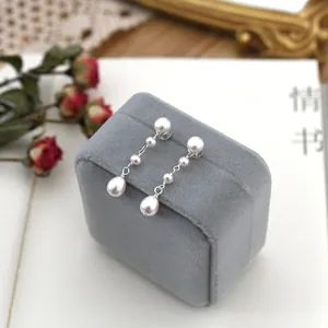 Close-up detail showing elegant freshwater pearl long drop earrings on a velvet jewelry box