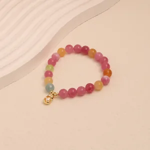 Close-up detail of a colorful fruit tourmaline beaded bracelet with gold pearl charm