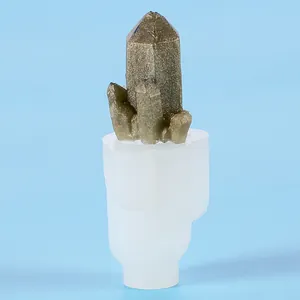 Detail view showing a white silicone mold with a finished golden resin crystal cluster on top.