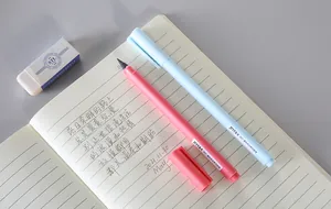 Macro detailed view of pink and blue inkless eternal pencils on an open notebook