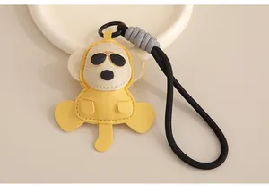 Détail d'un porte-clés singe en cuir jaune avec un cordon tressé noir élégant pour sac