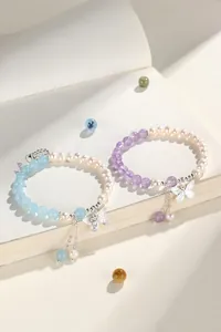 Close-up detail of natural freshwater pearl and crystal bead bracelets with butterfly charms