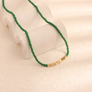 Dettaglio della collana di perle verdi retrò con barre dorate su supporto bianco