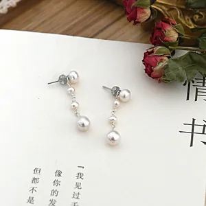 Close-up of elegant long drop earrings featuring lustrous white freshwater pearls