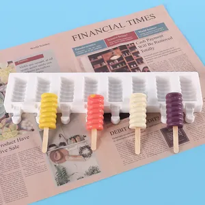 Close-up of white silicone popsicle mold with colorful spiral ice pops on newspaper