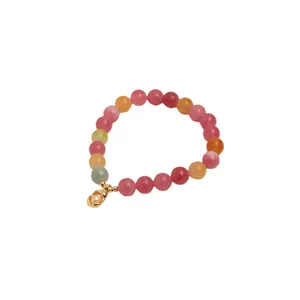 Vibrant multi-color beaded crystal bracelet with a gold pearl pendant on white background