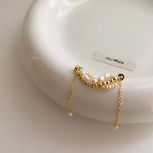 Detail view of magnetic ear cuff with freshwater pearls and tassels on white saucer.