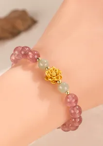 Detailed view of an elegant strawberry quartz lotus charm bracelet worn on an Asian wrist