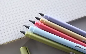 Close-up detail of five colorful inkless eternal pencils resting on a grid paper notebook