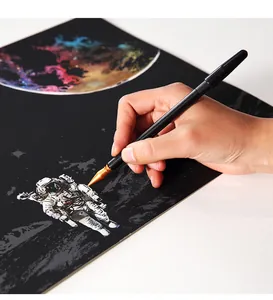 Nahaufnahme einer Hand mit einem goldenen Kratzstift auf einem Astronauten-Kratzbild für Erwachsene