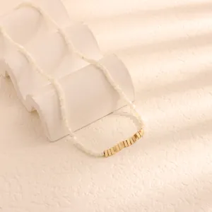 Primo piano dettagliato di una collana in perle di nacre con accenti dorati rettangolari