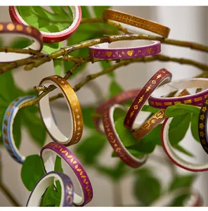 Close-up detail of gold foil washi tapes hanging on natural tree branches with leaves.