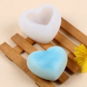 Vue détaillée du moule en silicone cœur 3D avec bougie bleue sur planche en bambou