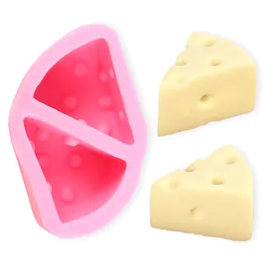 Detalle del molde de silicona rosa en forma de queso triangular con piezas de cera.
