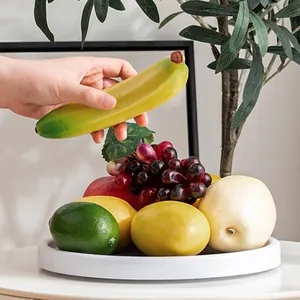 Vue détaillée d'un plateau de rangement rotatif blanc contenant des fruits artificiels