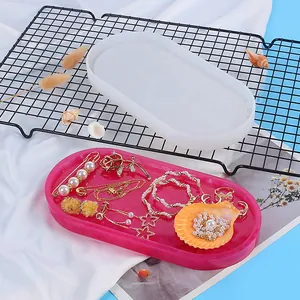 Detail view of oval silicone mold with finished pink resin tray and jewelry props