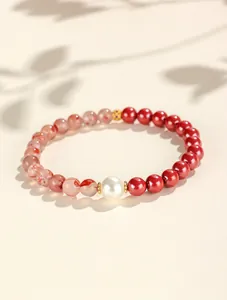 Detailed view of red cinnabar and agate beaded bracelet with a central white pearl accents.