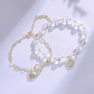 Goldfarbenes Armband-Set mit Mond- und Sternanhängern und durchscheinenden Perlen.