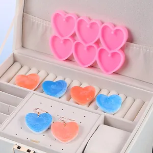 Vista dettagliata di stampi in silicone a cuore e orecchini in resina marmorizzata in portagioie