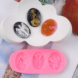 Detailed view of pink silicone mold with 3 vintage skeleton and angel relief cavities