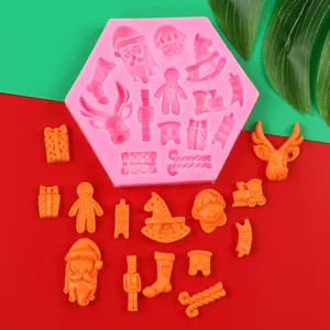 Detail of pink Christmas silicone mold with orange festive shapes on red and green background