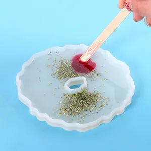 Irregular wavy silicone resin mold being filled with glitter and red pigment for DIY crafts.