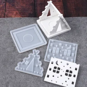 Close-up of silicone molds and finished white Christmas cabin candle holder parts.