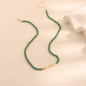 Dettaglio della collana di perline in pietra verde con accenti quadrati dorati.