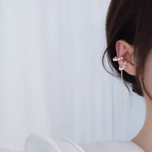 Gros plan d'un ear cuff plaqué or 14 carats avec perles naturelles et chaîne à pampilles