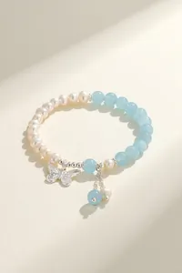 Detailed view of handmade pearl and aquamarine bracelet with silver butterfly charm