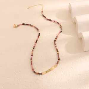 Dettaglio di una collana di perline in pietra naturale colorata con accenti dorati.