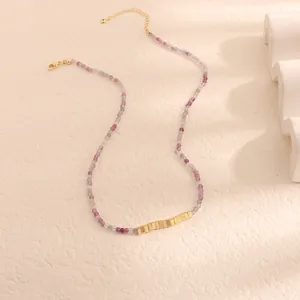 Dettaglio macro di una collana vintage con pietre naturali viola e segmenti d'oro