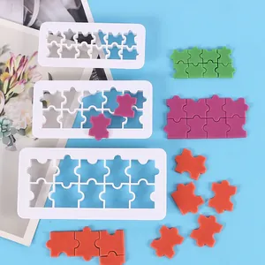 Detail of three puzzle shape cookie cutters and colorful fondant cutouts on blue