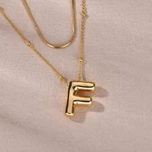 Detailed macro view of a stylish gold layered necklace with puffy balloon letter F pendant