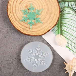 Close-up of a snowflake silicone mold alongside a green translucent resin ornament.