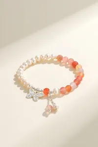 Elegant detailed shot of a handmade pearl and agate bracelet with a silver butterfly charm.