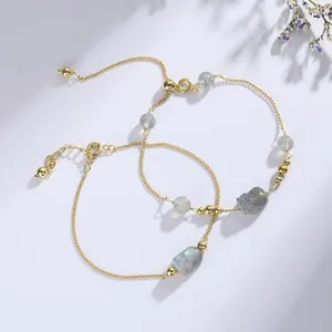 Detailansicht eleganter goldener Armbänder mit schimmernden blauen Katzenaugen-Steinen.