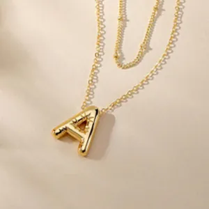 Close-up view of a minimalist gold initial A pendant on a delicate beaded satellite chain