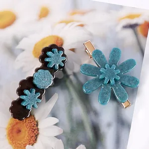 Détail montrant des barrettes en résine avec des motifs de fleurs bleues