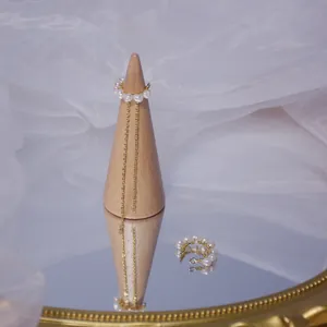 Détail d'un ear cuff en perles plaqué or 14k fait main avec un délicat gland en chaîne