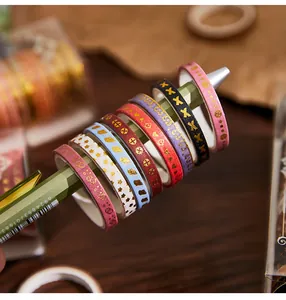 Detailed macro shot of gold foil washi tape set with various decorative patterns on pen