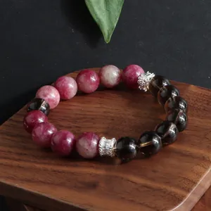 Primer plano detallado de pulsera de turmalina rosa y cuarzo ahumado sobre madera